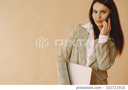 Woman in a studio. Lady with a laptop. Brunette in a brown jacket. 102721918