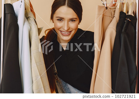 Woman on a brown background. Lady with clothes on a hanger. 102721921