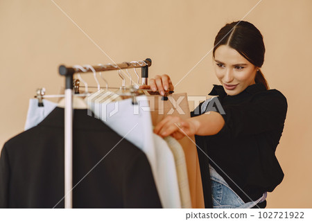 Woman on a brown background. Lady with clothes on a hanger. 102721922