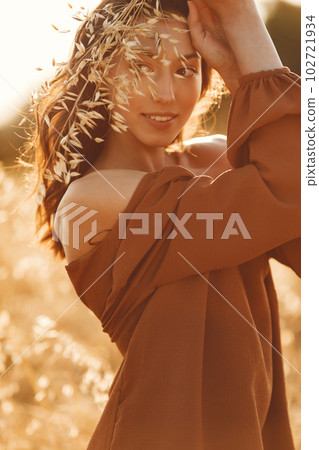 Woman in a summer field. Brunette in a brown sweater. Girl on a sunset background. 102721934