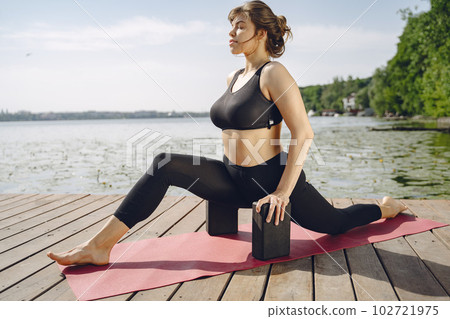 Pretty lady training in a summer park. Brunette doing yoga. Girl in a sportsuit. Pretty lady training in a summer park. Brunette doing yoga. Girl in a sportsuit. 102721975