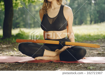 Pretty lady training in a summer park. Brunette doing yoga. Girl in a sportsuit. 102721987