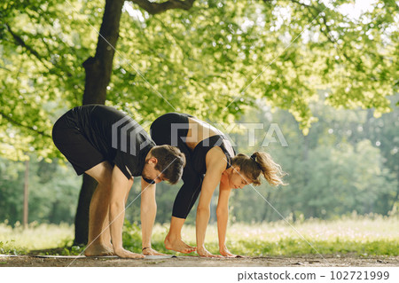 Young sportive couple doing yoga fitness . People in a summer park. 102721999