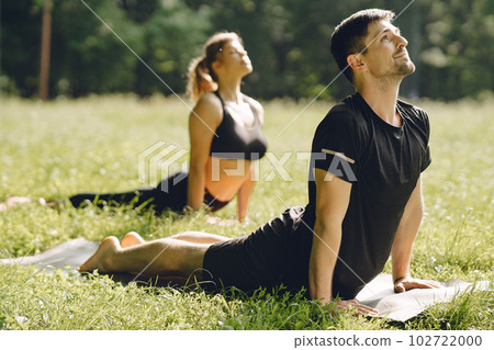 Young sportive couple doing yoga fitness . People in a summer park. Young sportive couple doing yoga fitness . People in a summer park. 102722000