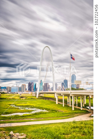 The Margaret Hunt Hill Bridge in Dallas, Texas stands as a stunning landmark amidst the cityscape, its long exposure and clouds contrasting against the built structure. 102722456