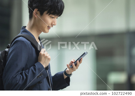 A young man looking at the screen of a smartphone 102722490