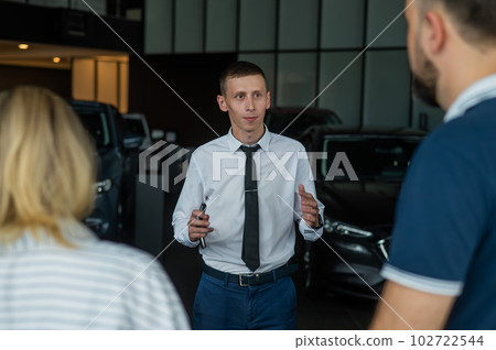 Happy caucasian couple choosing a new car in a car dealership. Happy caucasian couple choosing a new car in a car dealership. 102722544