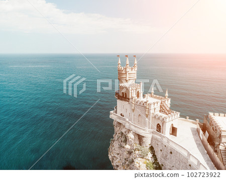 Crimea Swallow's Nest Castle on the rock over the Black Sea. It is a tourist attraction of Crimea. Amazing aerial view of the Crimea coast with the castle above abyss on sunny day. Crimea Swallow's Nest Castle on the rock over the Black Sea. It is a tourist attraction of Crimea. Amazing aerial view of the Crimea coast with the castle above abyss on sunny day. 102723922