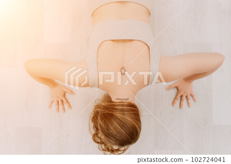 Young sporty woman, fitness instructor in sportswear doing stretching and pilates on yoga mat in the studio with mirror. Female fitness yoga routine concept. Healthy lifestyle and harmony. Young sporty woman, fitness instructor in sportswear doing stretching and pilates on yoga mat in the studio with mirror. Female fitness yoga routine concept. Healthy lifestyle and harmony. 102724041