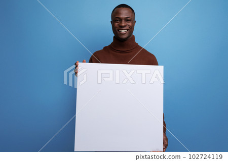 young brunet american man holding white sheet for advertisement space or important announcement 102724119
