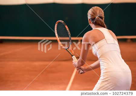View from the back on a female tennis player on a court indoor 102724379