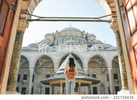 A young female traveler with a backpack on her back walks towards the Fatih Mosque in Istanbul. 102726016