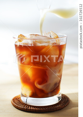 將冷牛奶倒入冰茶中。 將冷牛奶倒入冰茶中。 102726512