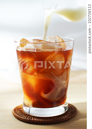 Pour cold milk into iced tea. 102726513