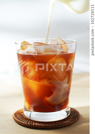 將冷牛奶倒入冰茶中。 102726515