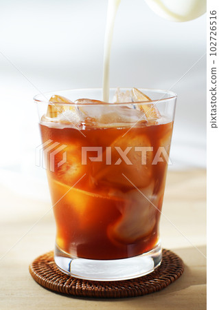 Pour cold milk into iced tea. 102726516