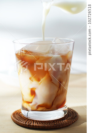 Pour cold milk into iced tea. 102726518