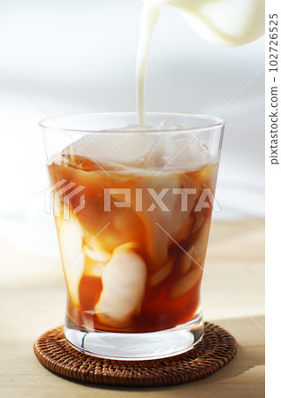 將冷牛奶倒入冰茶中。 102726525