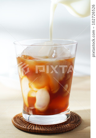 將冷牛奶倒入冰茶中。 102726526