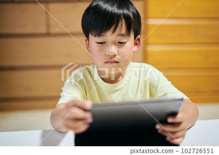 Elementary school boy watching videos on tablet Elementary school boy watching videos on tablet 102726551