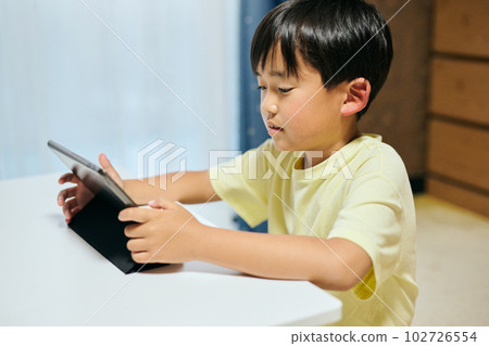 Elementary school boy watching videos on tablet Elementary school boy watching videos on tablet 102726554
