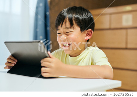Elementary school boy watching videos on tablet Elementary school boy watching videos on tablet 102726555