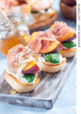 Prosciutto peach bruschetta, crostini with cream cheese, basil leaf, peach and prosciutto, vertical Prosciutto peach bruschetta, crostini with cream cheese, basil leaf, peach and prosciutto, vertical 102728476