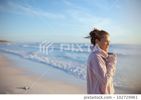 relaxed stylish woman in cosy sweater at beach in evening relaxed stylish woman in cosy sweater at beach in evening 102729961