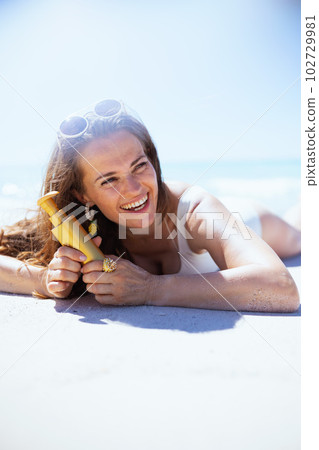 smiling elegant woman with sunscreen laying at beach smiling elegant woman with sunscreen laying at beach 102729981