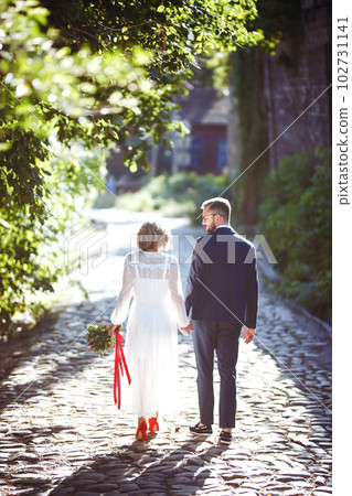 Couple enjoying romantic moments while walking in park. Stylish bride and groom posing and kissing. Couple enjoying romantic moments while walking in park. Stylish bride and groom posing and kissing. 102731141