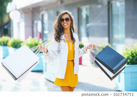 Fashion woman with shopping bags walking on street. Spring Style. Consumerism, shopping, lifestyle. Fashion woman with shopping bags walking on street. Spring Style. Consumerism, shopping, lifestyle. 102734751