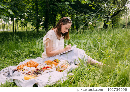 Beautiful woman on picnic. She smiles, eats strawberries and enjoys summer. Beautiful woman on picnic. She smiles, eats strawberries and enjoys summer. 102734996