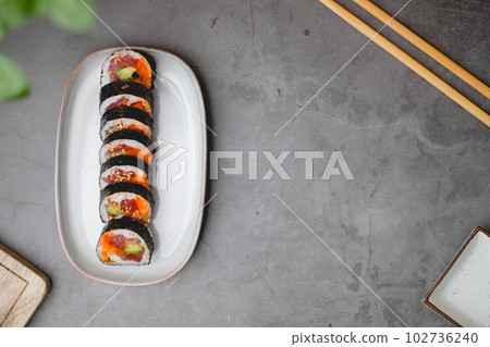 Top view of sushi rolls of tuna, cucumber, and avocado with copy space of the black concrete table. 102736240