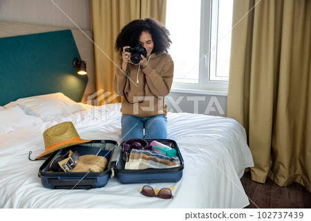 Young woman making pictures of suitcase on the bed 102737439