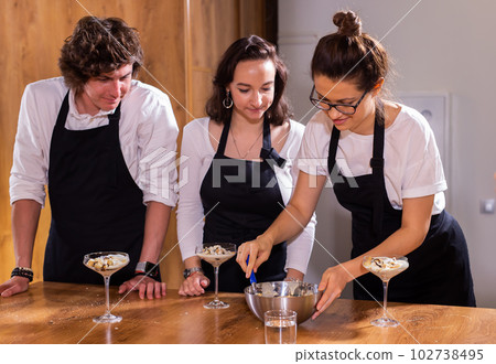 Chef teaching trainees how to make ice cream. Cooking tasty ice cream dessert made from chocolate and vanilla in glass bowl 102738495