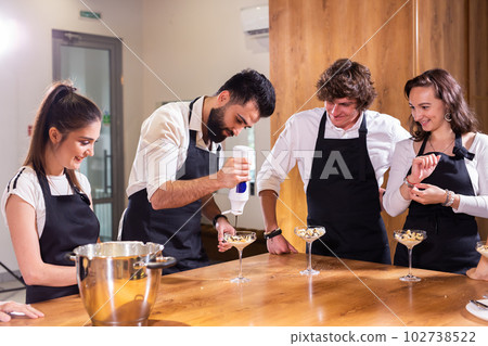 Chef teaching trainees how to make ice cream. Cooking tasty ice cream dessert made from chocolate and vanilla in glass bowl 102738522