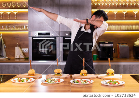 Portrait happy funny chef with cooked meals for a dinner party in the kitchen Portrait happy funny chef with cooked meals for a dinner party in the kitchen 102738624