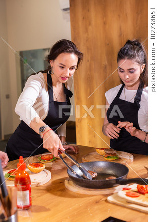 Preparing delicious burgers. Chef cooking meat burgers with beef, cheese and vegetables. Close-up Preparing delicious burgers. Chef cooking meat burgers with beef, cheese and vegetables. Close-up 102738651