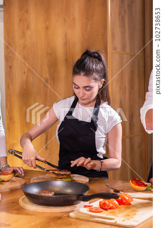 Female Preparing delicious burgers. Chef cooking meat burgers with beef, cheese and vegetables. Close-up Female Preparing delicious burgers. Chef cooking meat burgers with beef, cheese and vegetables. Close-up 102738653