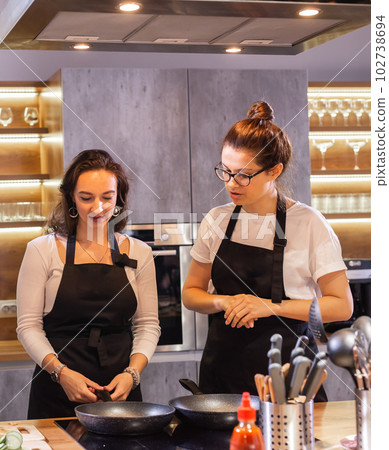 Two funny professional female chefs cooking food in large kitchen 102738694