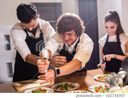 Funny Chef sprinkles with paprika over caprese salad in restaurant kitchen 102738707