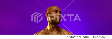 Man with athletic body performs exercises using resistance band on studio background 102738739