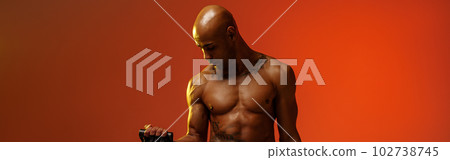Sporty man performs exercises with expander on studio background. Strength and motivation Sporty man performs exercises with expander on studio background. Strength and motivation 102738745