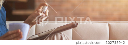 Close up shot of woman disinfecting and cleaning digital device, tablet pc from microbes, viruses and bacteria with a disinfectant 102738942