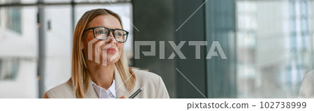 Businesswoman architect in glasses working on project while sitting in cafe and looking at window Businesswoman architect in glasses working on project while sitting in cafe and looking at window 102738999