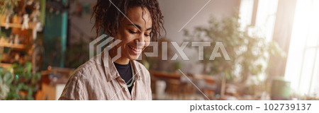 Smiling Woman working in home decor studio with elements of interior decorations. Blurred background Smiling Woman working in home decor studio with elements of interior decorations. Blurred background 102739137