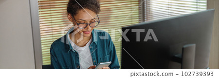 Smiling woman interior designer holding smartphone during break at home office. Freelance concept 102739393