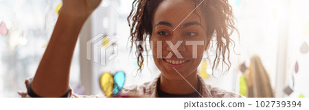 Smiling woman holding handmade glass decoration in the form of heart standing in home decor studio 102739394