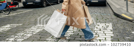 Fashion afro american woman after shopping with paper bags crosses road and looking at camera 102739410
