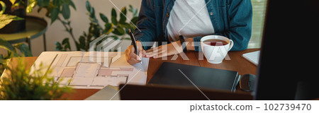 Smiling Afro american woman interior designer in headphones works with documents in home office Smiling Afro american woman interior designer in headphones works with documents in home office 102739470